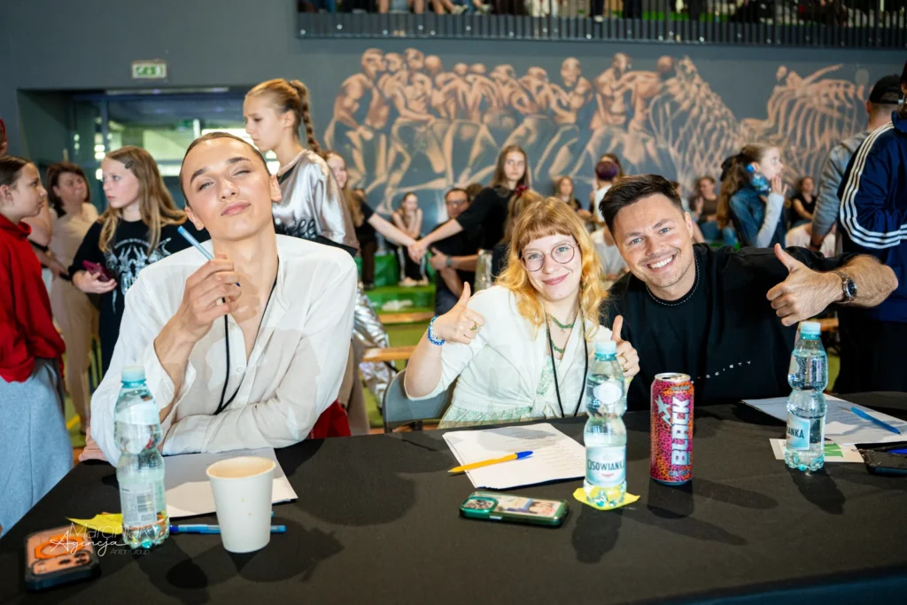 Trzy osoby z jury przy stoliku sędziowskim podczas turnieju Manner Dance