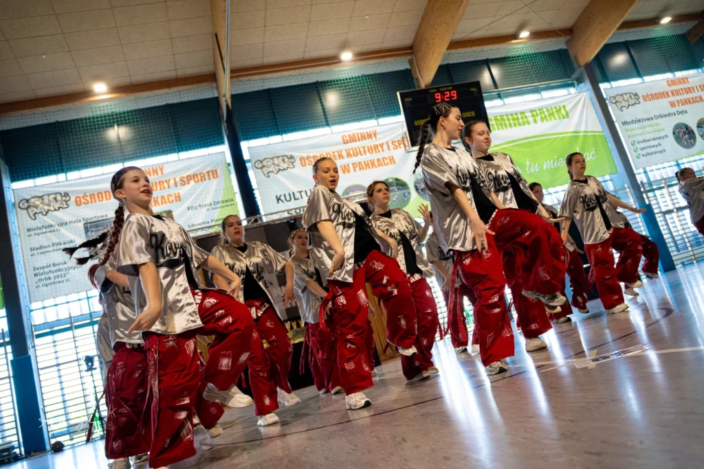 Zespół w srebrnych koszulkach i czerwonych spodniach podczas występu na turnieju Manner Dance